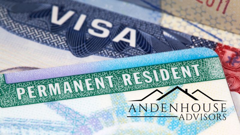 Close-up shot of a United States "Permanent Resident" Green Card layered over a visa document, featuring the Andenhouse Advisors corporate logo in the lower right corner.